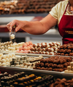 Ladenmitarbeiterin die gerade Pralinen für einen Kunden zusammenstellt