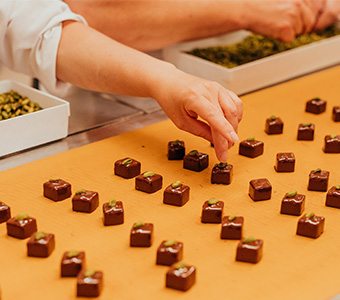 Mitarbeiter die gerade Pistazien auf Pralinen platzieren
