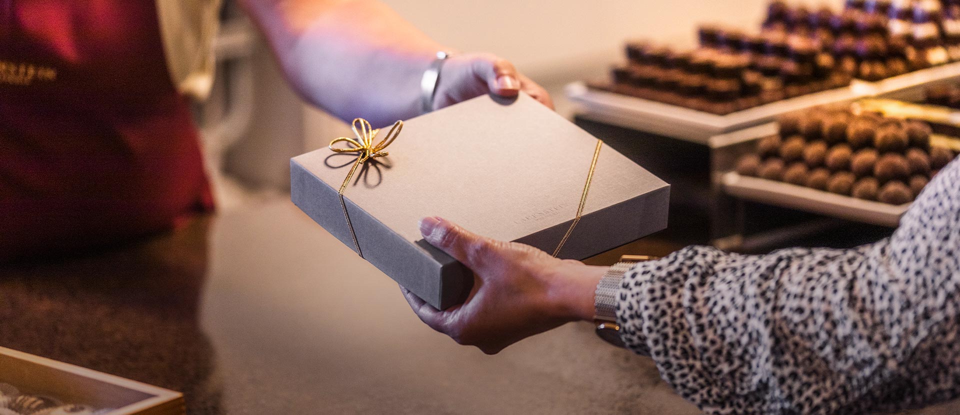 Verkäuferin gibt Kundin eine schön verpackte Pralinenschachtel